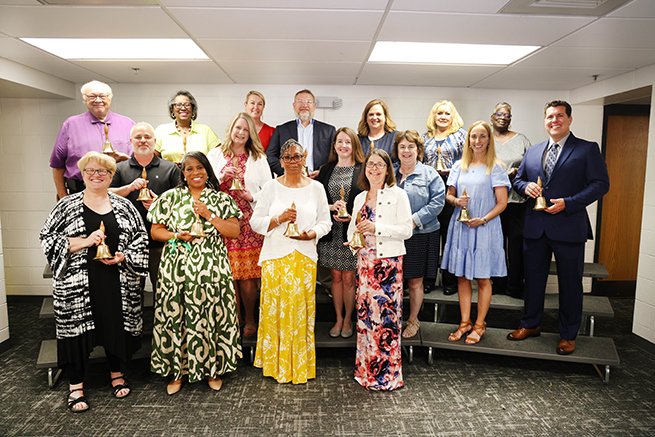 Staff who are retiring stand with their retirement bells